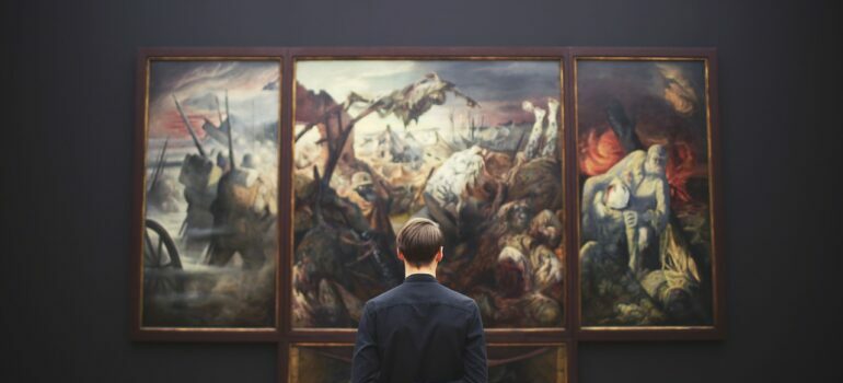 A man in black shirt admiring paintings.