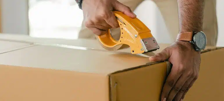 person sealing a moving box