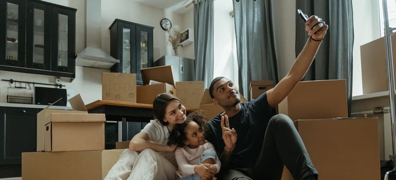 Parents and daughter taking a selfie next to moving boxes