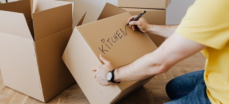 a man writing a word kitchen on a box