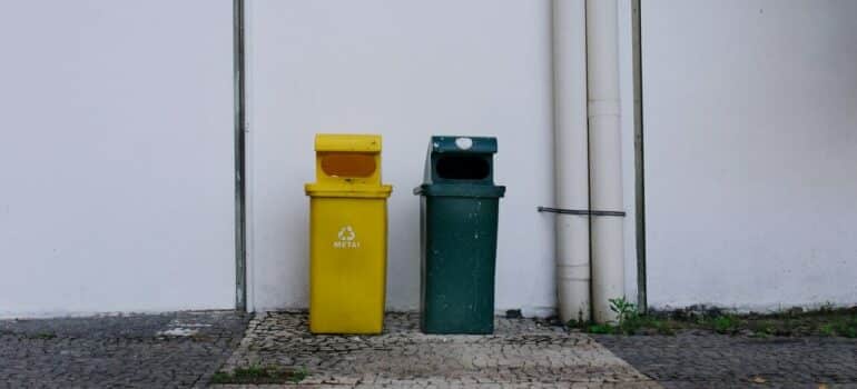 two garbage bins for metal and plastic placed beside a building
