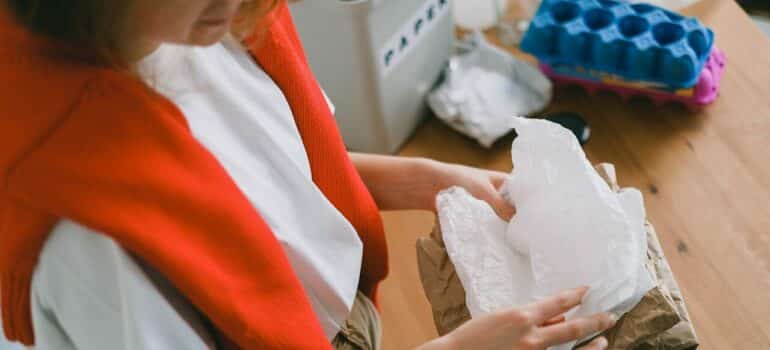 a woman folding plastic and paper to reduce waste at home as she packs