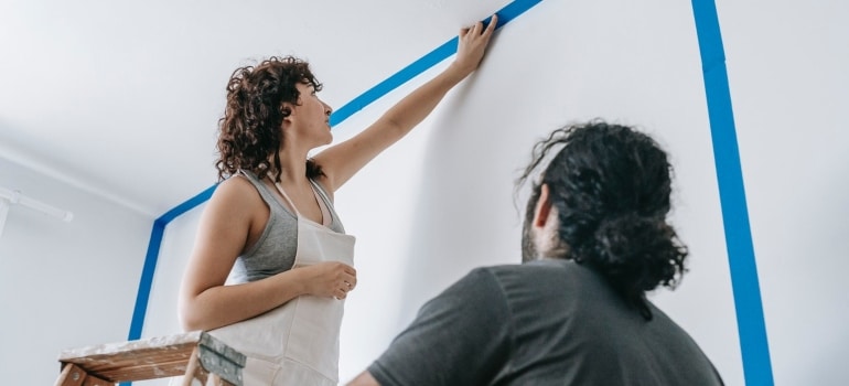 a couple painting a wall together to represent budget-friendly home improvements you can implement