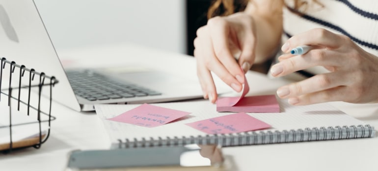 a woman writing things down on pink sticky notes