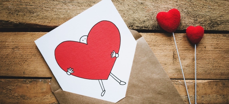 a card with a drawn man holding a big red heart