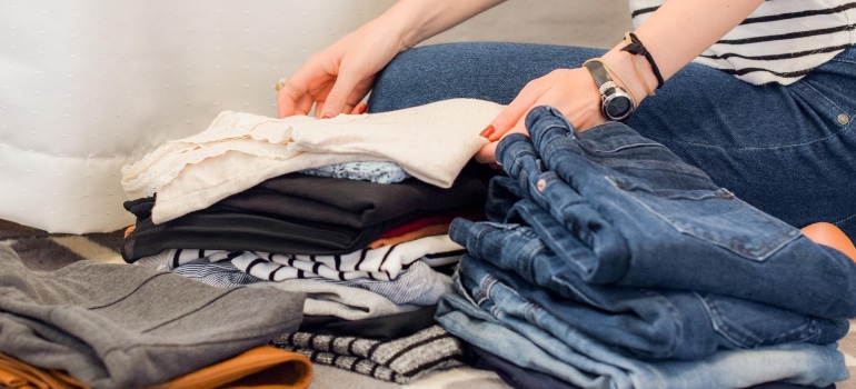 a woman folding her wardrobe to depict ways to create additional storage space in your home