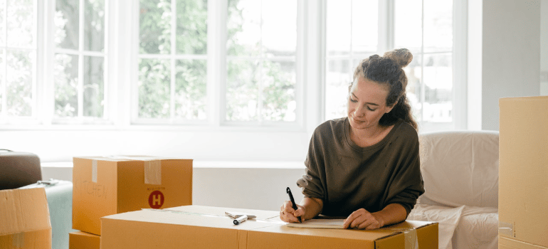 a woman writing down on a box