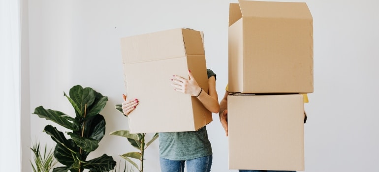 two people holding moving boxes