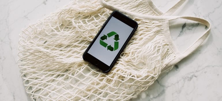 Eco-friendly packing bag and a phone with a recycle logo on it;