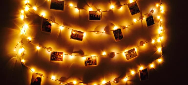 Photos hanging on the frame with a lot of tiny lamps behind them;