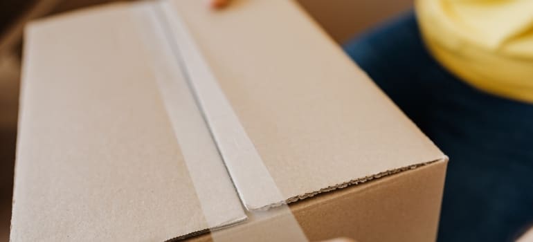Person sealing a cardboard box