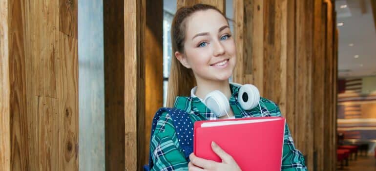 Girl with headphones and books in the hall 