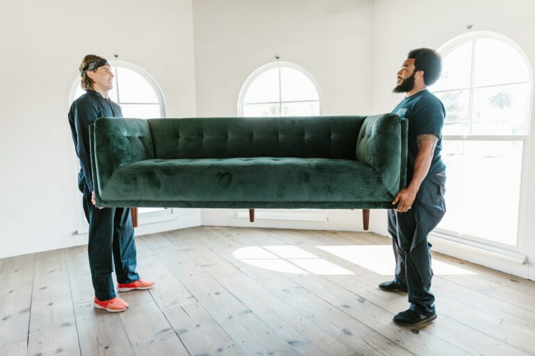 Two professional movers carrying large couch 