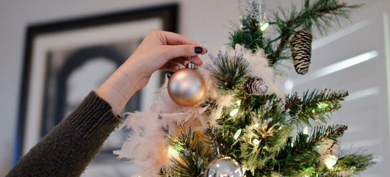 A hand placing an ornament on a Christmas tree
