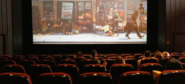Inside of a cinema with chairs and movie showing on the screen 