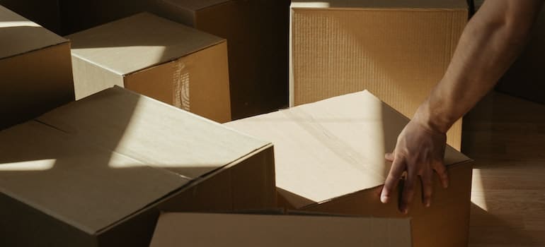 A person preparing a pile of moving boxes for storage after reading the guide to different types of storage