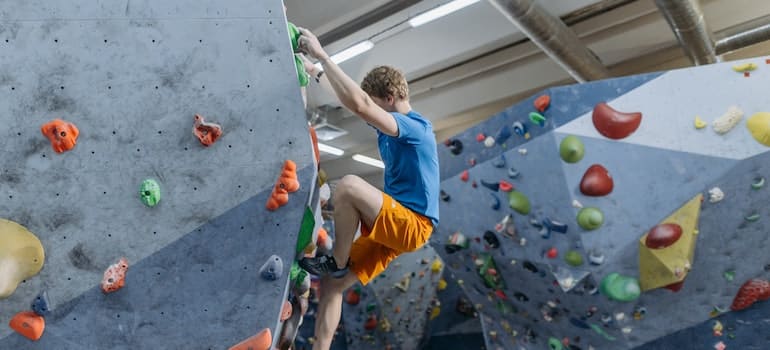 A person climbing an indoor rock while visiting Austin in winter
