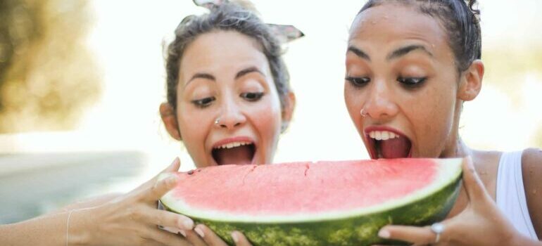 Two girls eating a watermelon slice to survive Texas summers